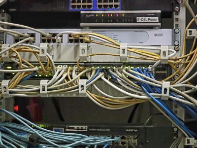 带宽测试主编林砚舟坐在堆满路由器与网线的工位前，屏幕上是数据看板风格的速率曲线，侧光勾勒出专注的轮廓，氛围冷静克制